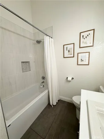 a white bath tub sitting next to a white toilet and vanity