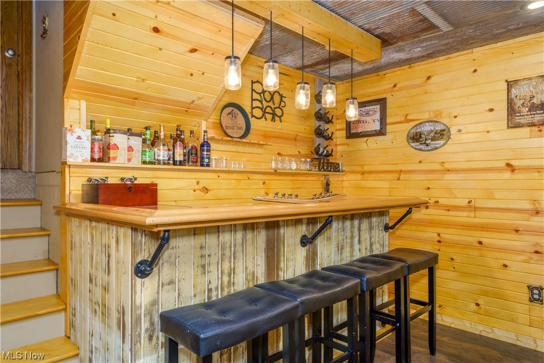 8646 Yale Road Rootstown, OH 44272 - Photo 7 of 30 Bar featuring dark hardwood / wood-style flooring, butcher block countertops, wooden ceiling, hanging light fixtures, and wooden walls