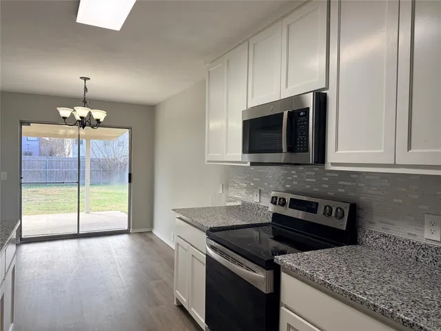 a kitchen with granite countertop a stove a sink and a microwave