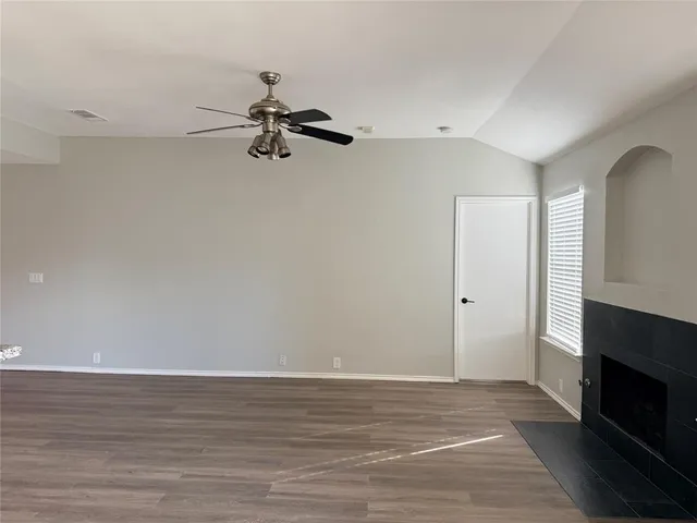 a view of an empty room with wooden floor and a fireplace