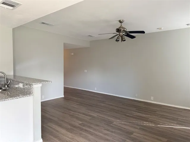 an empty room with wooden floor cabinet and windows