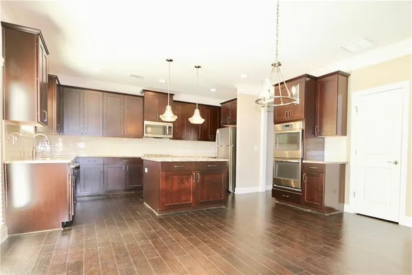 a large kitchen with a wooden floor and stainless steel appliances
