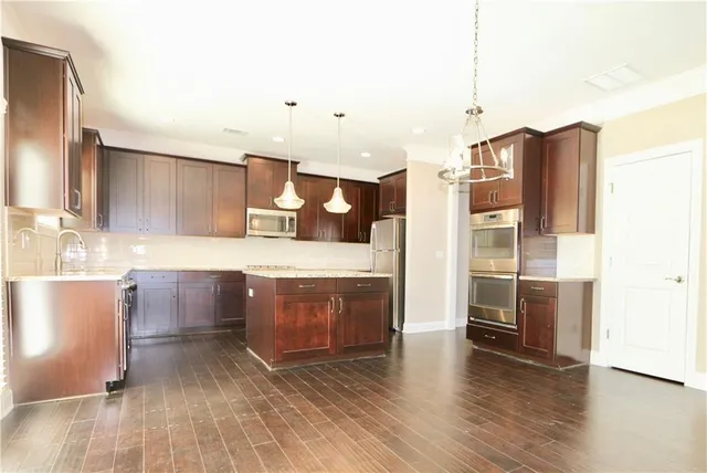 a large kitchen with a wooden floor and stainless steel appliances