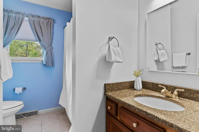 a bathroom with a granite countertop sink toilet and a mirror