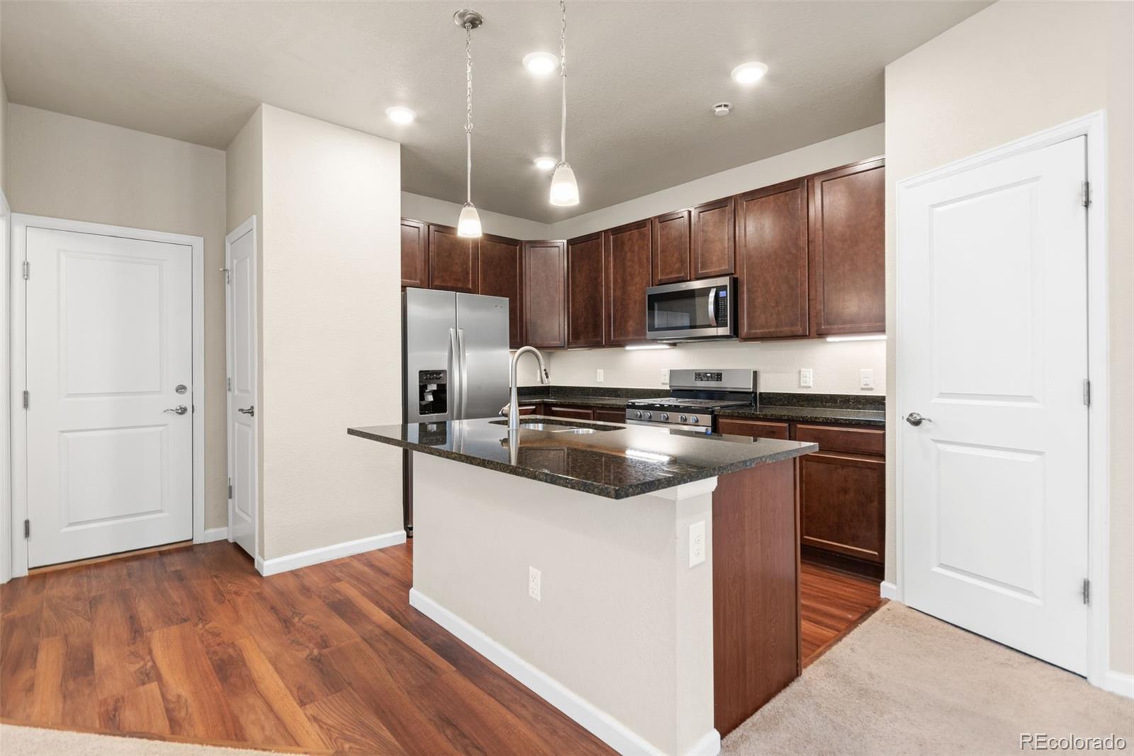 8417 Rizza Street, Unit A Littleton, CO 80129 - Photo 24 of 30 a kitchen with kitchen island a sink stainless steel appliances and cabinets