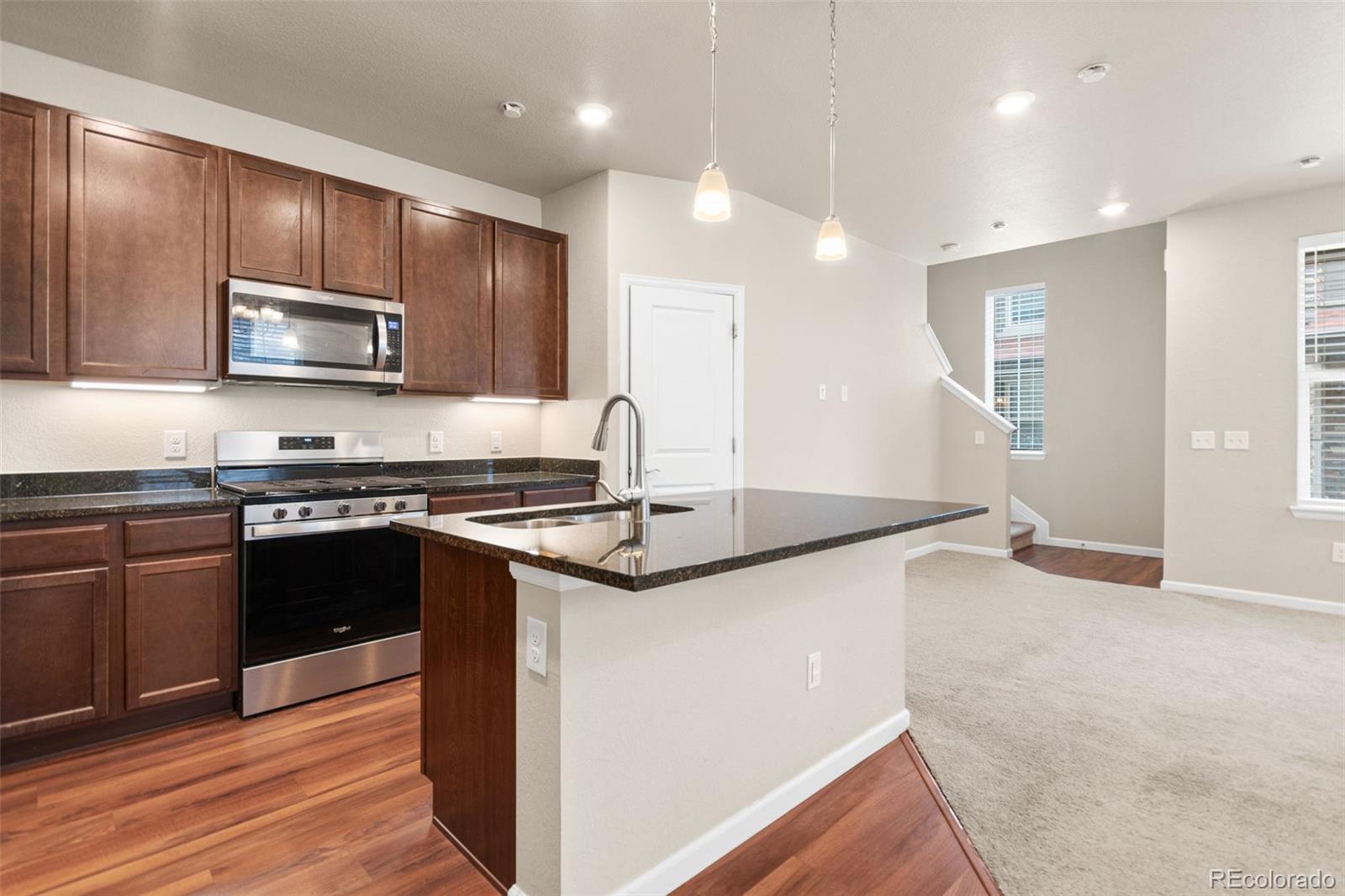 8417 Rizza Street, Unit A Littleton, CO 80129 - Photo 25 of 30 a kitchen with stainless steel appliances granite countertop a sink stove microwave and cabinets