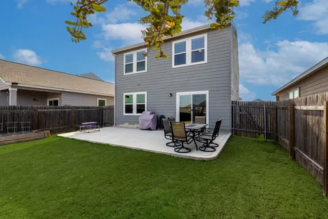 a view of a backyard with table and chairs potted plants and a wooden fence