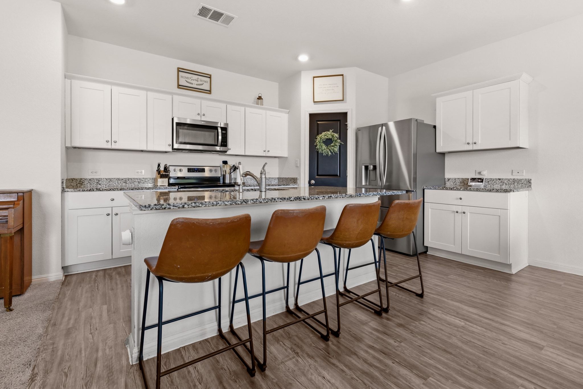 212 Wonderful Life Way Jarrell, TX 76537 - Photo 3 of 25 Kitchen with white cabinets, stainless steel appliances, dark stone countertops, a center island with sink, and a kitchen bar