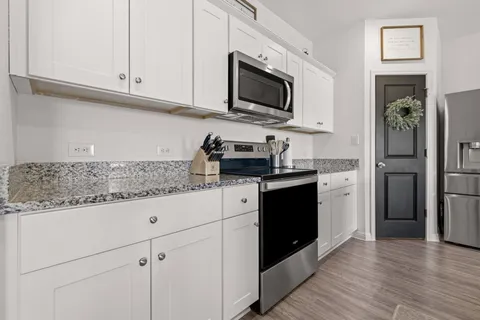 a kitchen with granite countertop white cabinets and stainless steel appliances
