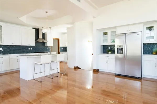 a kitchen with stainless steel appliances granite countertop a refrigerator a oven a sink and white cabinets with wooden floor