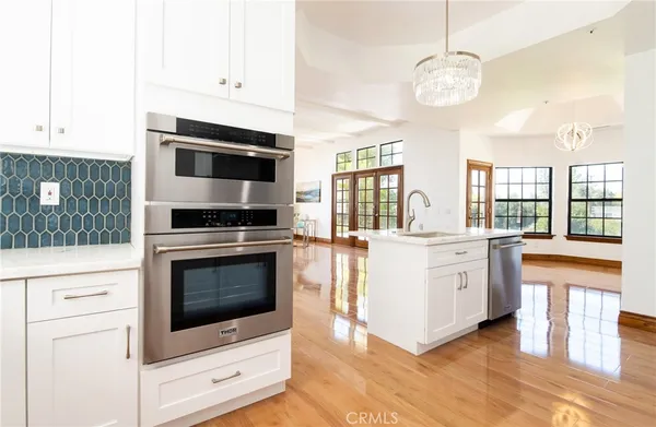 a kitchen with stainless steel appliances granite countertop a sink a stove and white cabinets