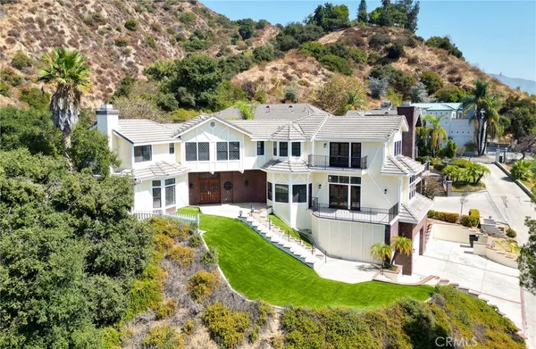 an aerial view of residential house with outdoor space and trees all around