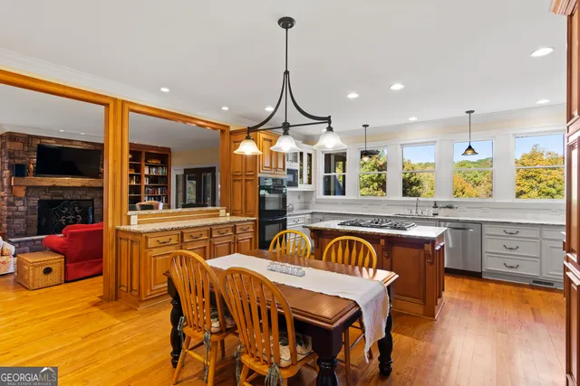 a kitchen with stainless steel appliances granite countertop a stove a sink a dining table and chairs with wooden floor