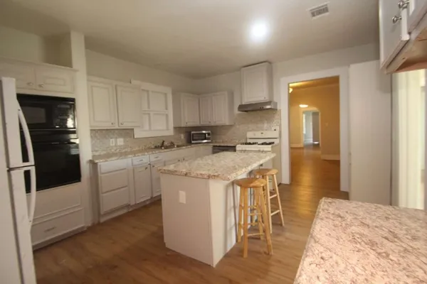 a kitchen with stainless steel appliances kitchen island granite countertop a stove a sink and a refrigerator