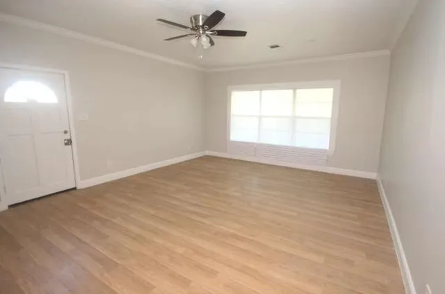 a view of empty room with wooden floor and fan