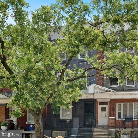 a front view of a house with a tree