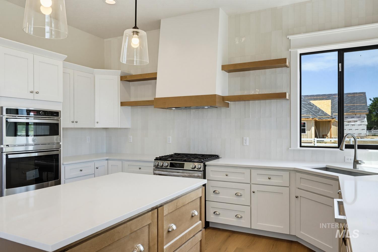 5054 Heritage Drive Marsing, ID 83639 - Photo 5 of 38 Modern kitchen featuring a central island with a white countertop, stainless steel appliances, white cabinetry, a built-in oven and microwave, and a gas range