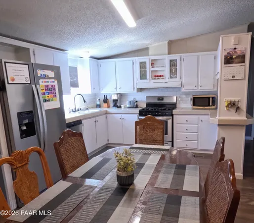 a kitchen with stainless steel appliances granite countertop a stove top oven a sink a dining table and chairs