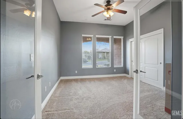 an empty room with windows and fan