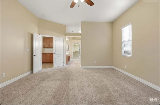 an empty room with chandelier fan and windows
