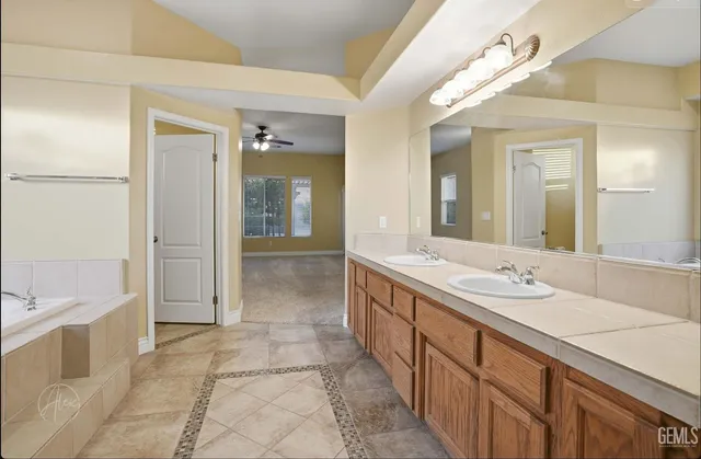 a spacious bathroom with a double vanity sink a large mirror and a bathtub