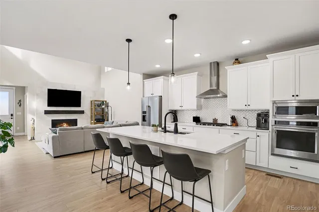 a kitchen with stainless steel appliances kitchen island granite countertop a sink a stove a dining table and chairs