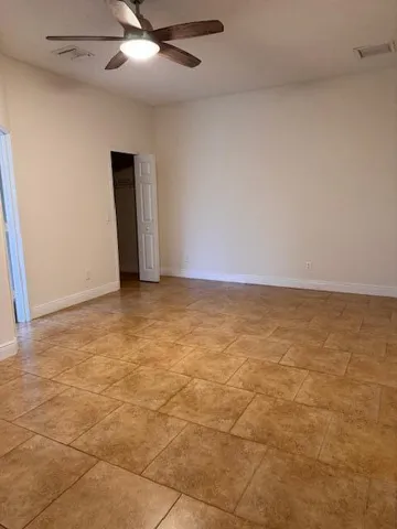 an empty room with a ceiling fan and carpet
