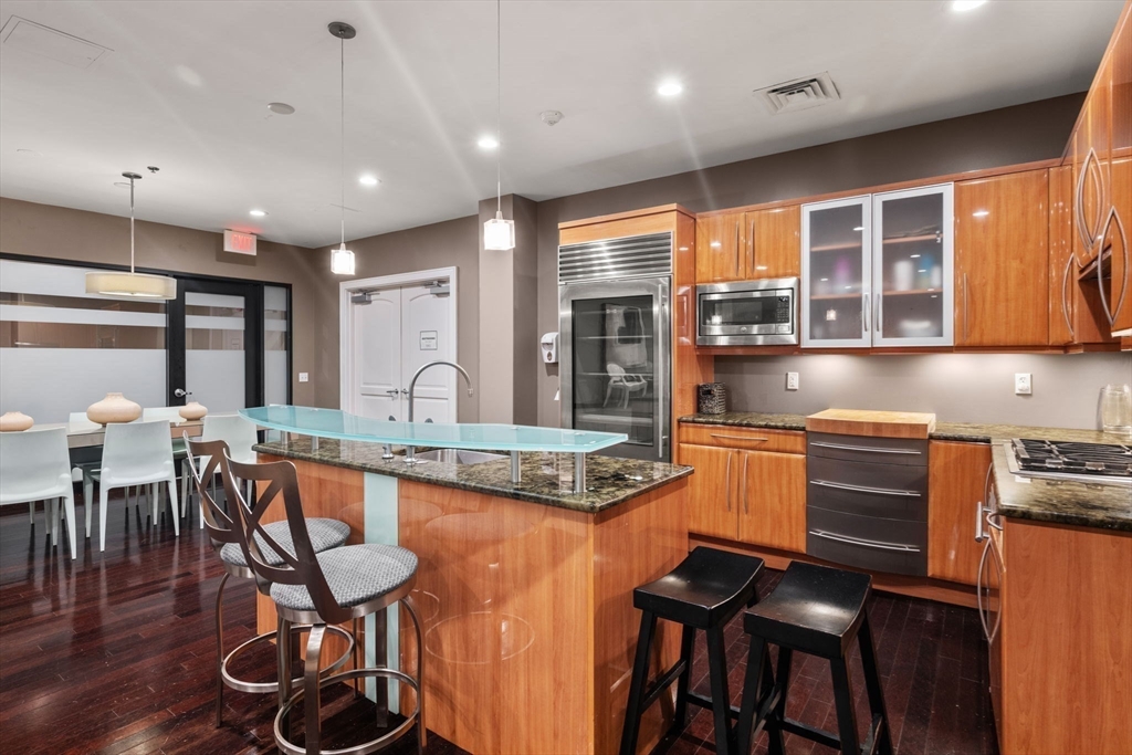 2420 Beacon Street, Unit 402 Boston, MA 02467 - Photo 28 of 29 a kitchen with stainless steel appliances granite countertop a stove top oven a sink a dining table and chairs with wooden floor