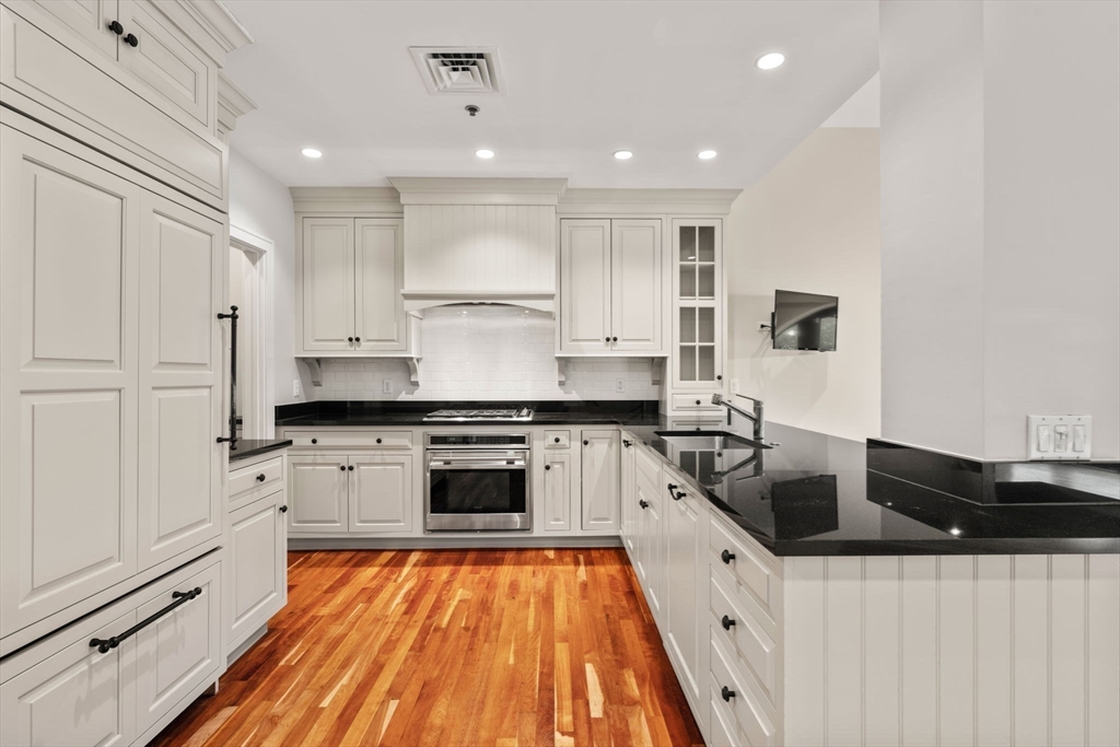 2420 Beacon Street, Unit 402 Boston, MA 02467 - Photo 7 of 29 a large kitchen with granite countertop a stove top oven a sink a counter space and cabinets