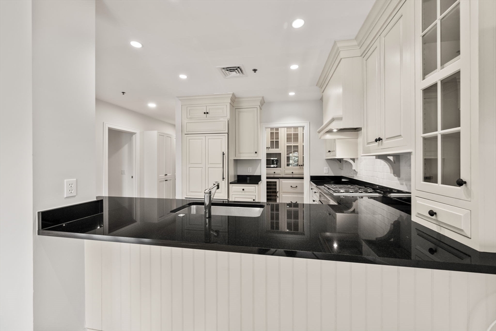 2420 Beacon Street, Unit 402 Boston, MA 02467 - Photo 9 of 29 a kitchen with stainless steel appliances granite countertop a sink dishwasher and white cabinets with wooden floor