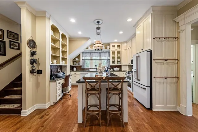 a kitchen with stainless steel appliances granite countertop a table chairs stove and wooden floor