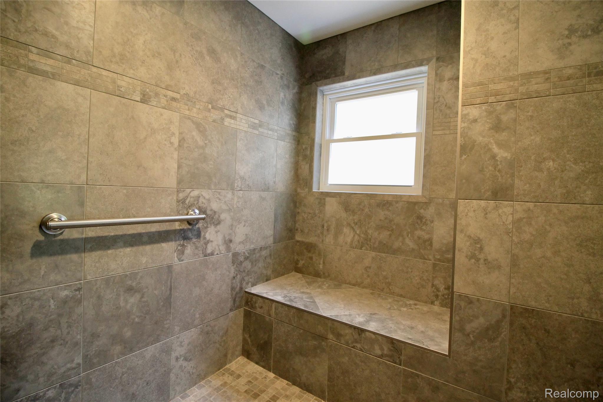 8372 Parshallville Road Fenton, MI 48430 - Photo 14 of 44 Tiled shower enclosure featuring a built-in bench, window with white trim, and a chrome grab bar