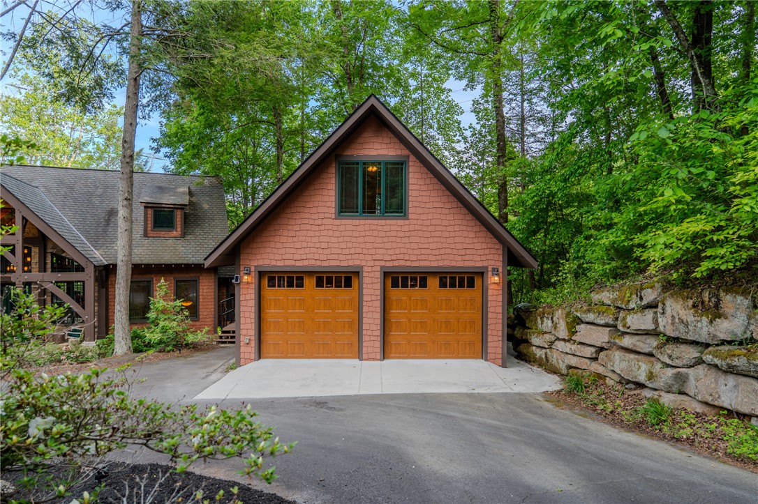 102 State Rd S-39-143 Sunset, SC 29685 - Photo 42 of 47 A rustic home with an attached garage is nestled among lush trees, featuring a paved driveway.