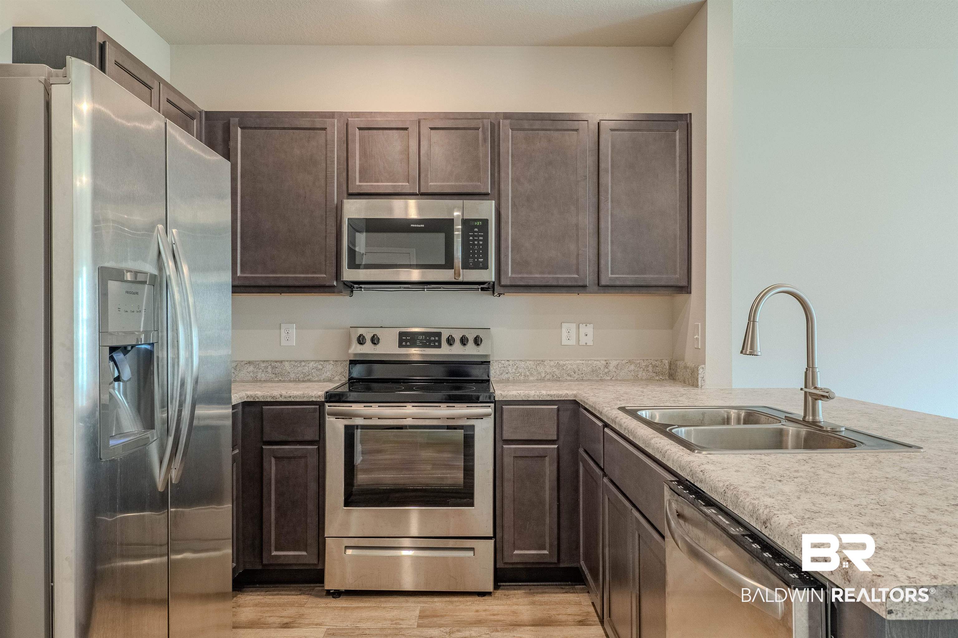25806 Pollard Road, Unit 32 Daphne, AL 36526 - Photo 6 of 23 Kitchen featuring dark brown cabinetry, sink, kitchen peninsula, light hardwood / wood-style flooring, and stainless steel appliances