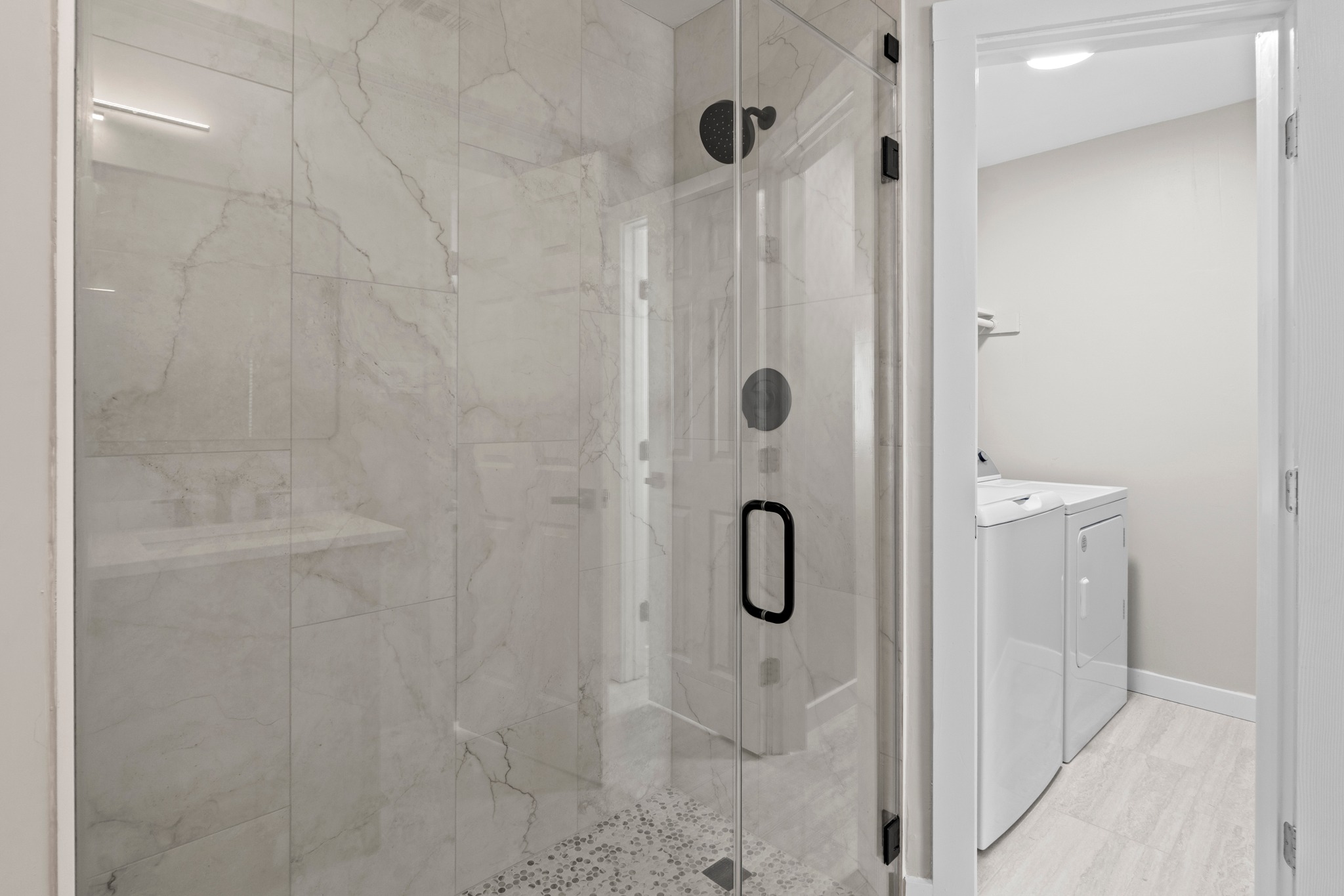 11811 Rotherham Drive Austin, TX 78754 - Photo 22 of 37 A sleek, contemporary shower enclosure boasts sophisticated marble-patterned tiling and modern fixtures.
