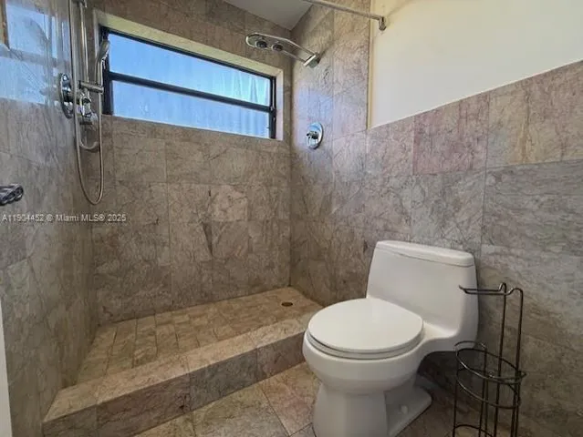 a white toilet sitting next to a bath tub and shower