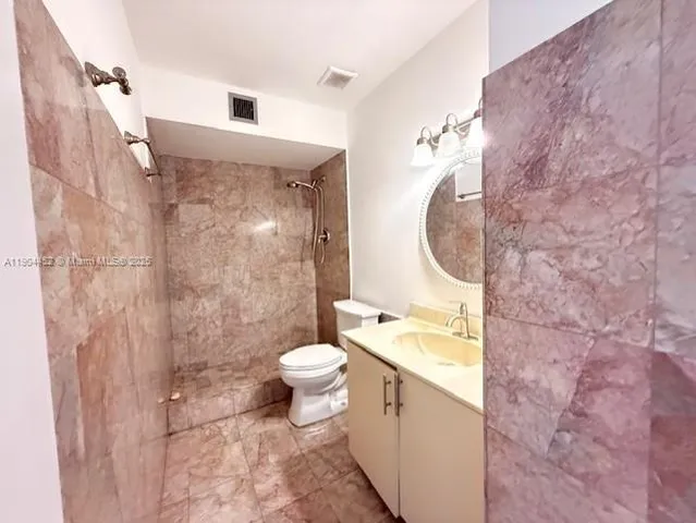 a bathroom with a granite countertop toilet a sink and a mirror