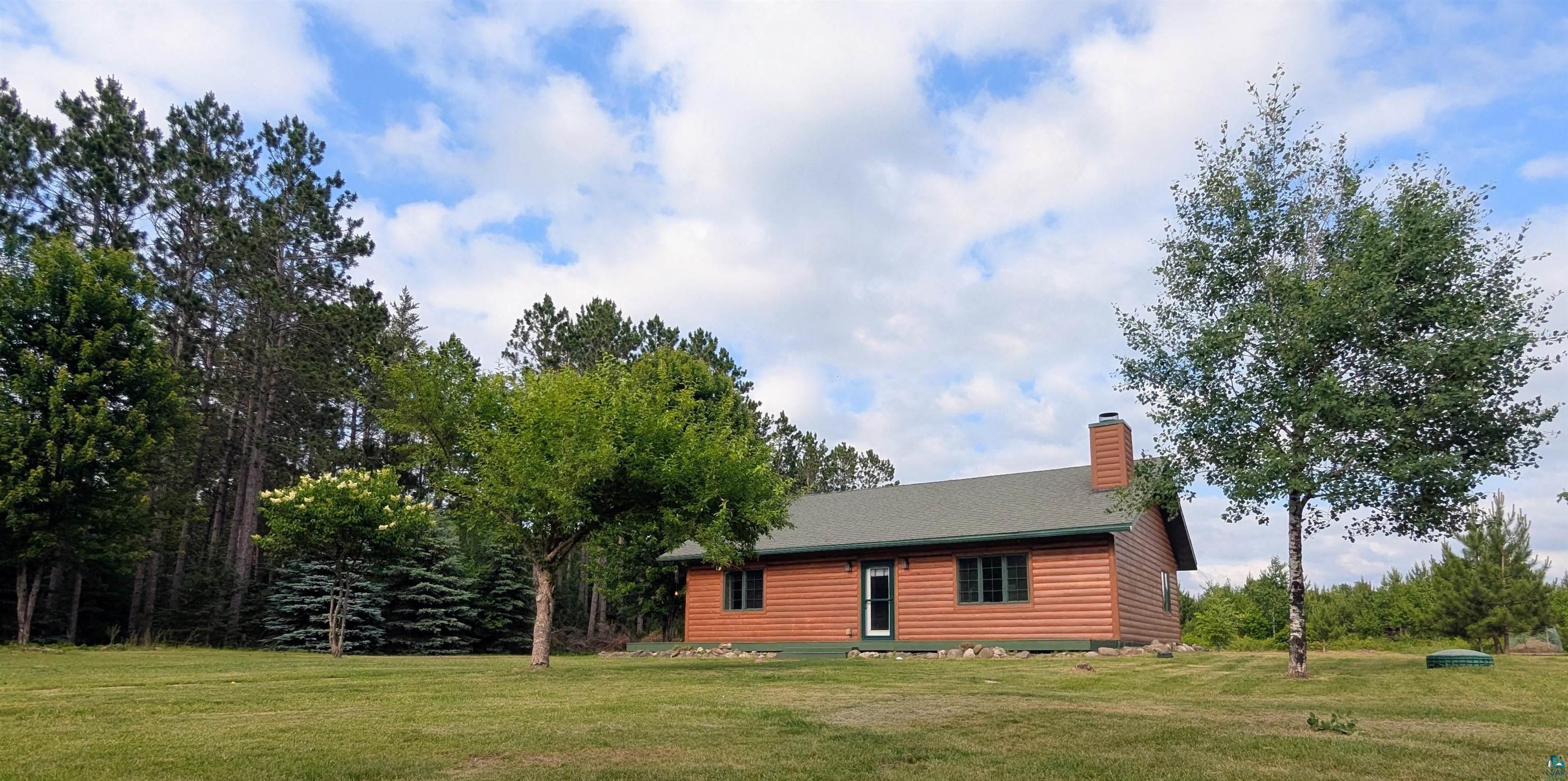 86196 Military Road Sturgeon Lake, MN 55783 - Photo 2 of 4 Wood-sided residence with green roofing and a prominent brick chimney