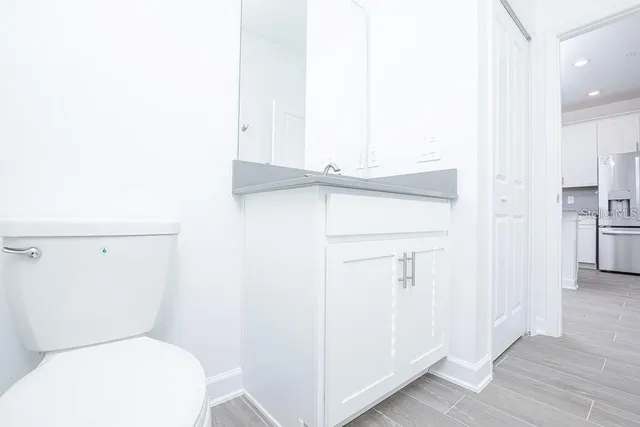 a bathroom with a granite countertop sink a mirror a toilet and shower