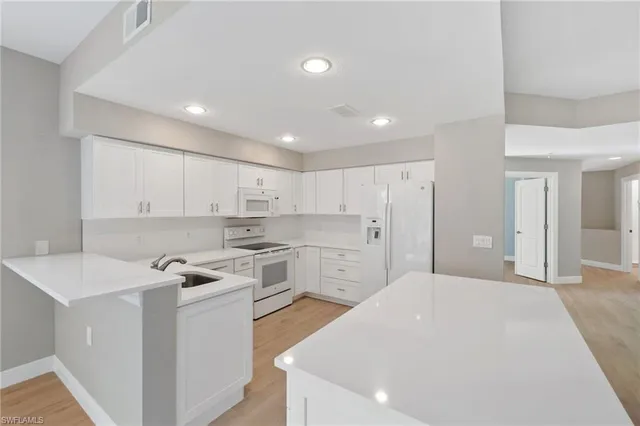 a kitchen with white cabinets and white appliances
