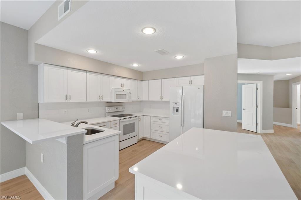 4995 Marsh Turtle Trail, Unit 102 Estero, FL 33928 - Photo 11 of 42 a kitchen with white cabinets and white appliances