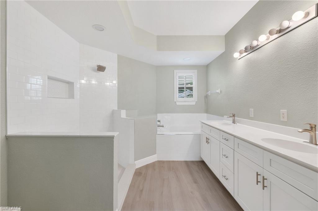 4995 Marsh Turtle Trail, Unit 102 Estero, FL 33928 - Photo 16 of 42 a bathroom with a tub sink and mirror