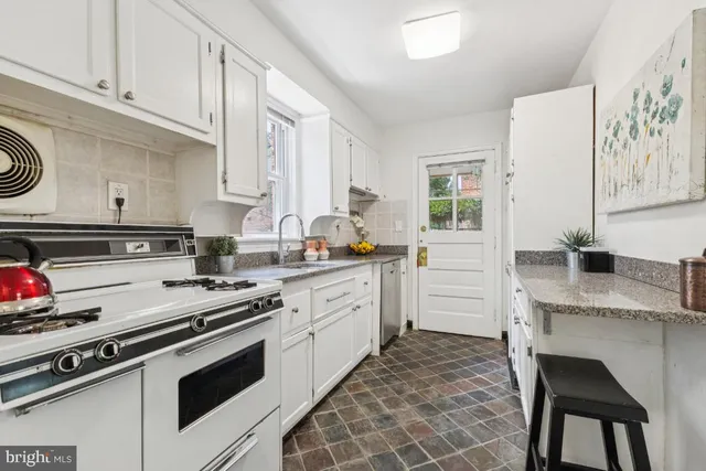 a kitchen with granite countertop white cabinets and white appliances