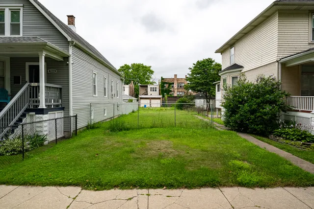 a backyard of a house with plants and wooden fence