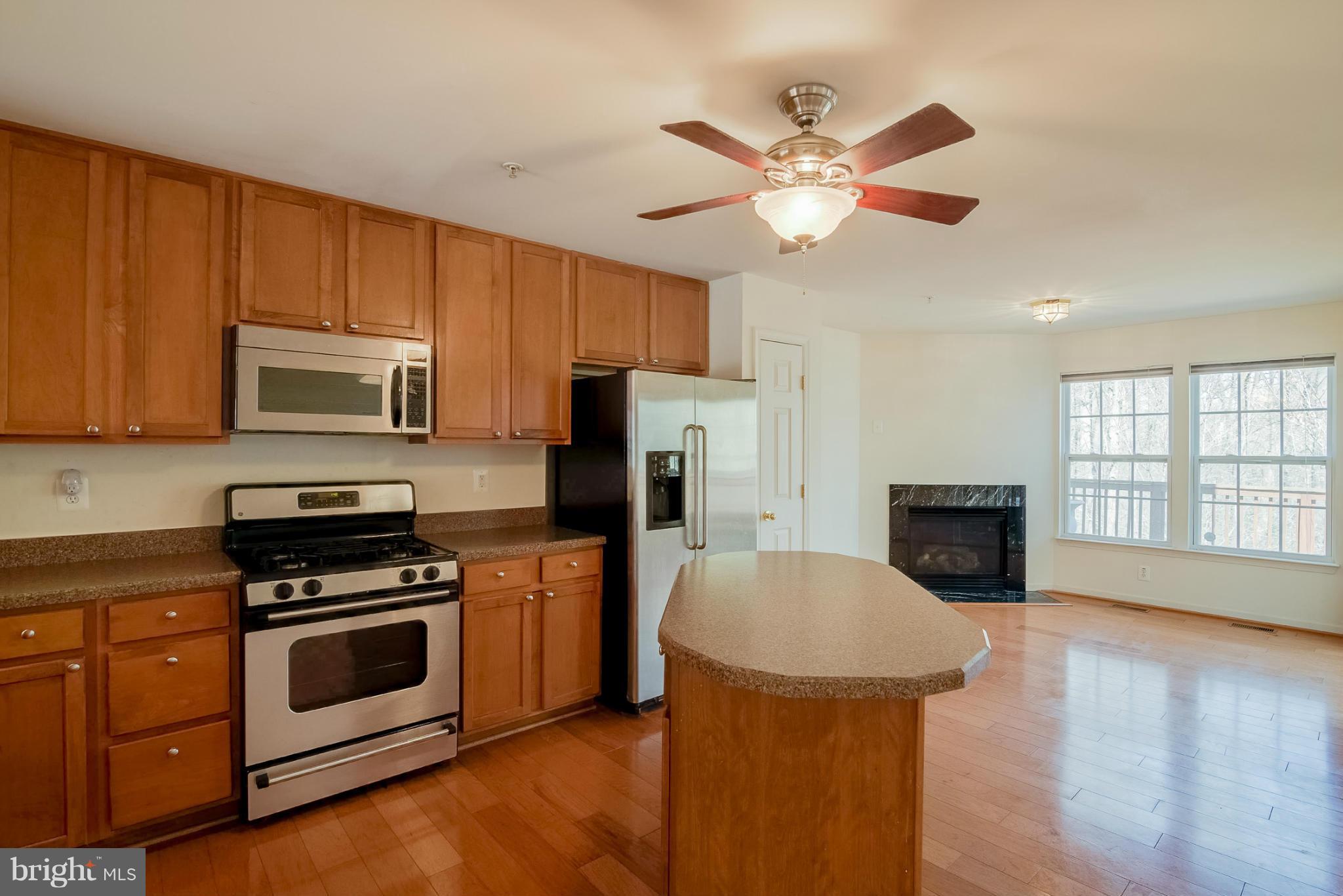 8103 Pennington Drive Laurel, MD 20724 - Photo 3 of 14 a kitchen with granite countertop a stove top oven a sink dishwasher a dining table and chairs with wooden floor