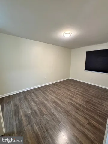 a view of an empty room with wooden floor and a fireplace