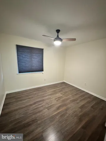 a view of an empty room with wooden floor and a ceiling fan