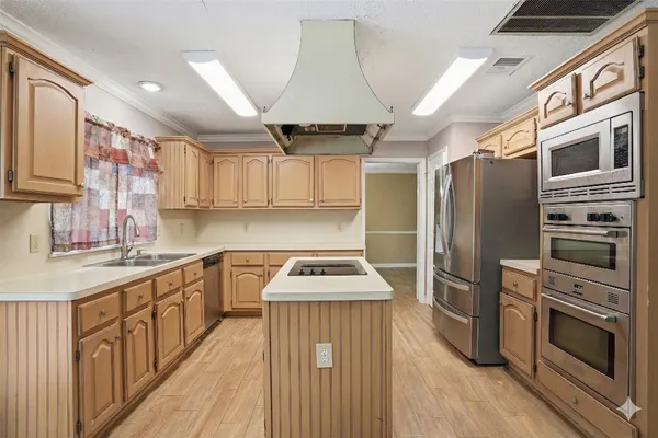 a kitchen with stainless steel appliances a stove a refrigerator a sink dishwasher and a stove with wooden floor