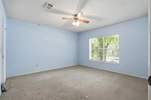 an empty room with a ceiling fan and window