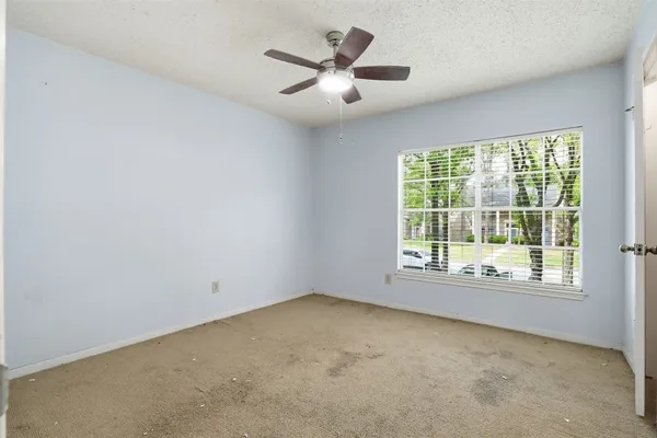 an empty room with a ceiling fan and window